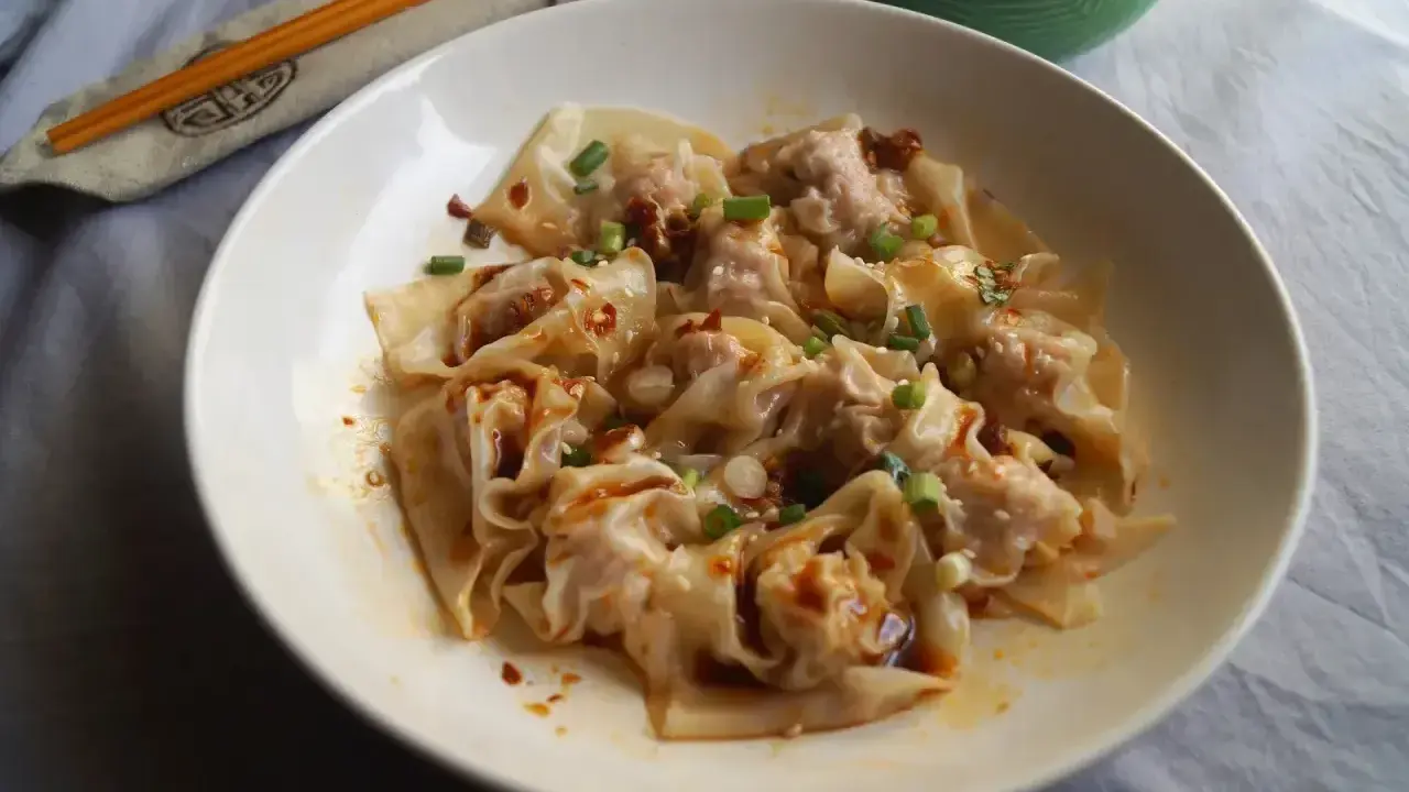 Pyszne pierożki wonton w pikantnym sosie, posypane szczypiorkiem i sezamem. Ciasto do wontonów jest cienkie i delikatne.