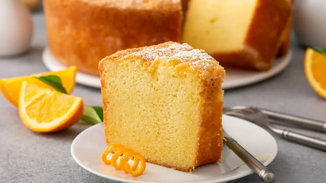 Puszysta babka cytrynowa, oprószona cukrem pudrem, z plasterkami pomarańczy. Idealna na niedzielne popołudnie, gdy szukasz przepisu na babkę wiszącą.