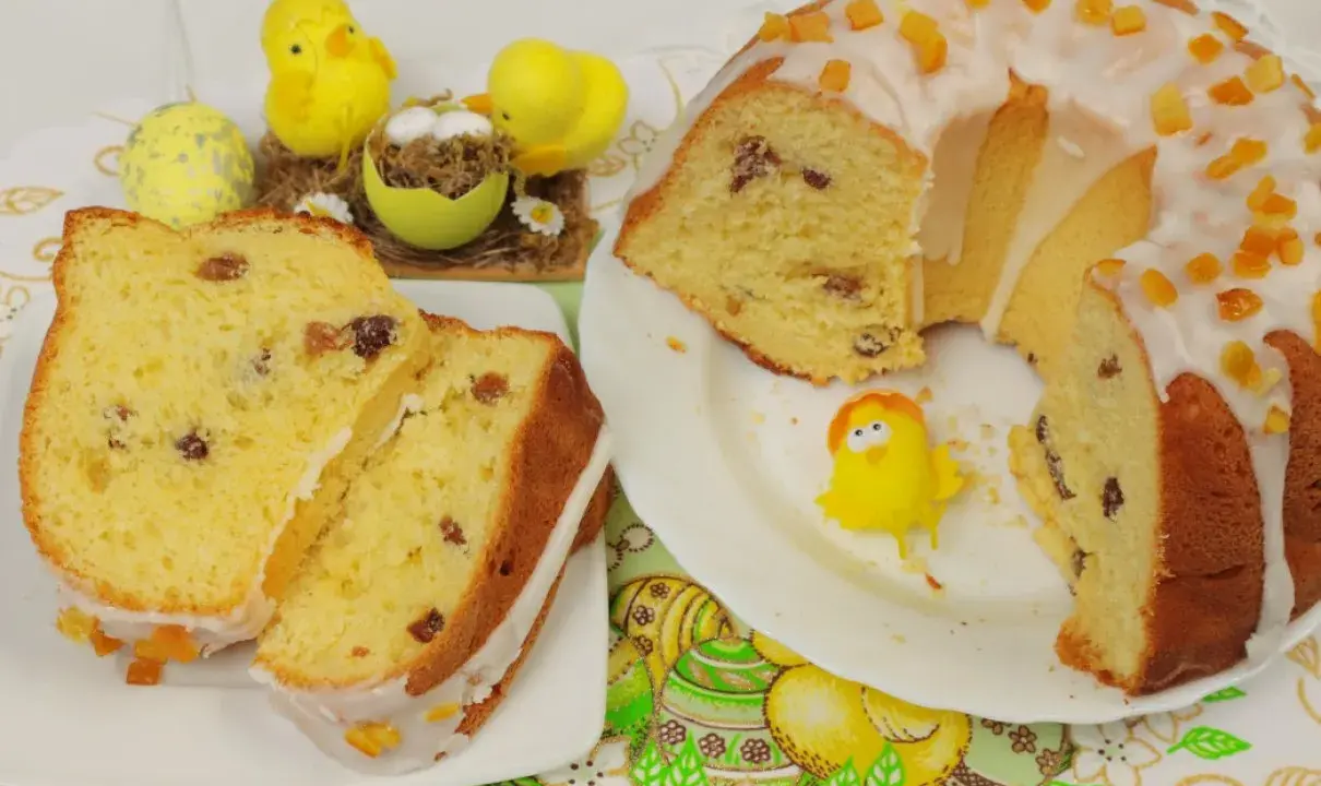Najłatwiejsza babka drożdżowa z rodzynkami, polana lukrem i ozdobiona kandyzowaną skórką pomarańczową. W tle wielkanocne kurczaczki i pisanki.