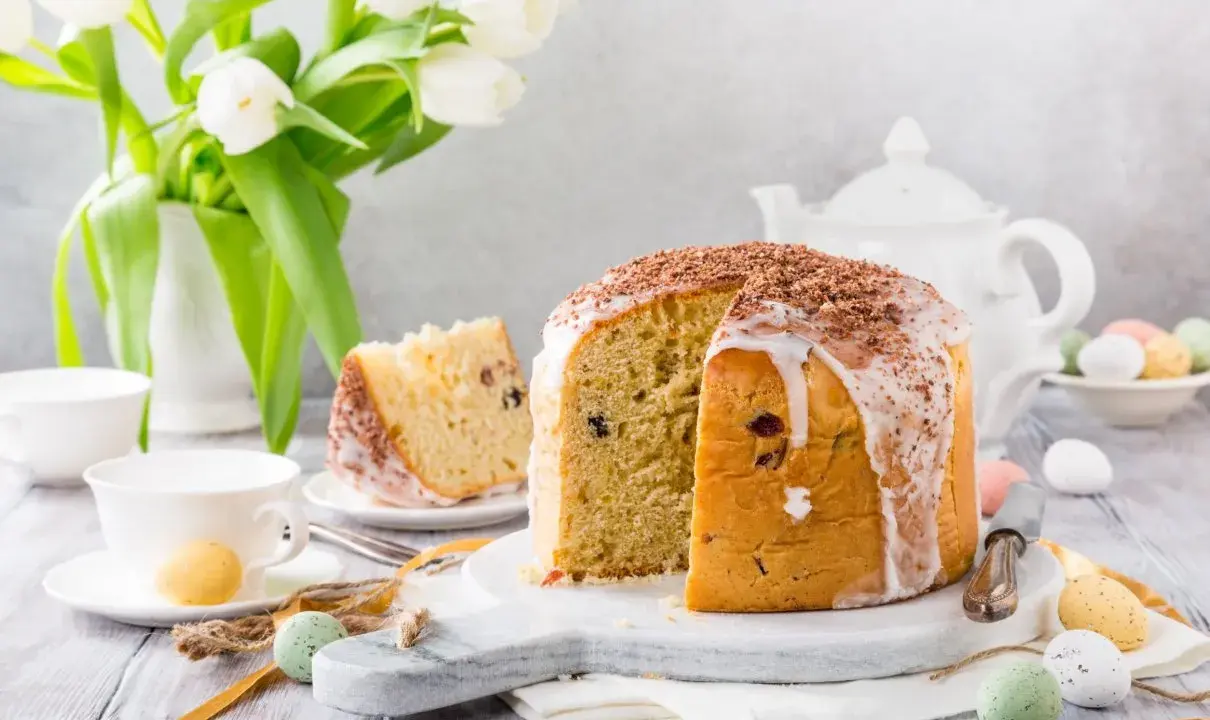 Pyszna babka włoska z lukrem i czekoladową posypką, udekorowana na Wielkanoc z tulipanami i kolorowymi jajeczkami.