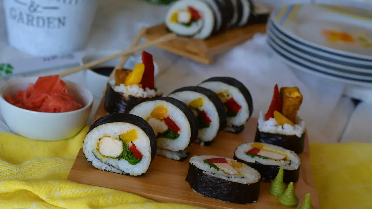 Pyszne sushi z kurczakiem, papryką i mango. Podane na desce z dodatkami: marynowanym imbirem i wasabi.
