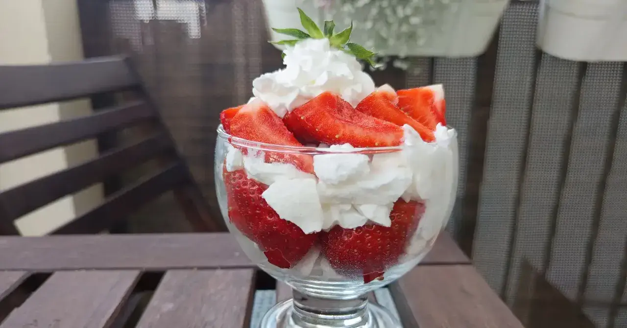 Pyszne, świeże truskawki ze śmietaną w pucharku, gotowe do schrupania.