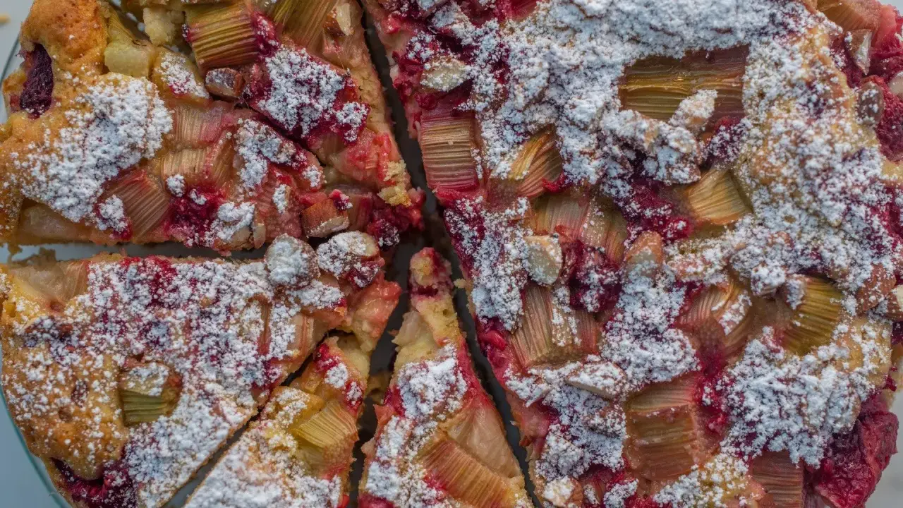 Pyszne ciasto z rabarbarem i malinami, posypane cukrem pudrem. Idealny przepis na letnie popołudnie.