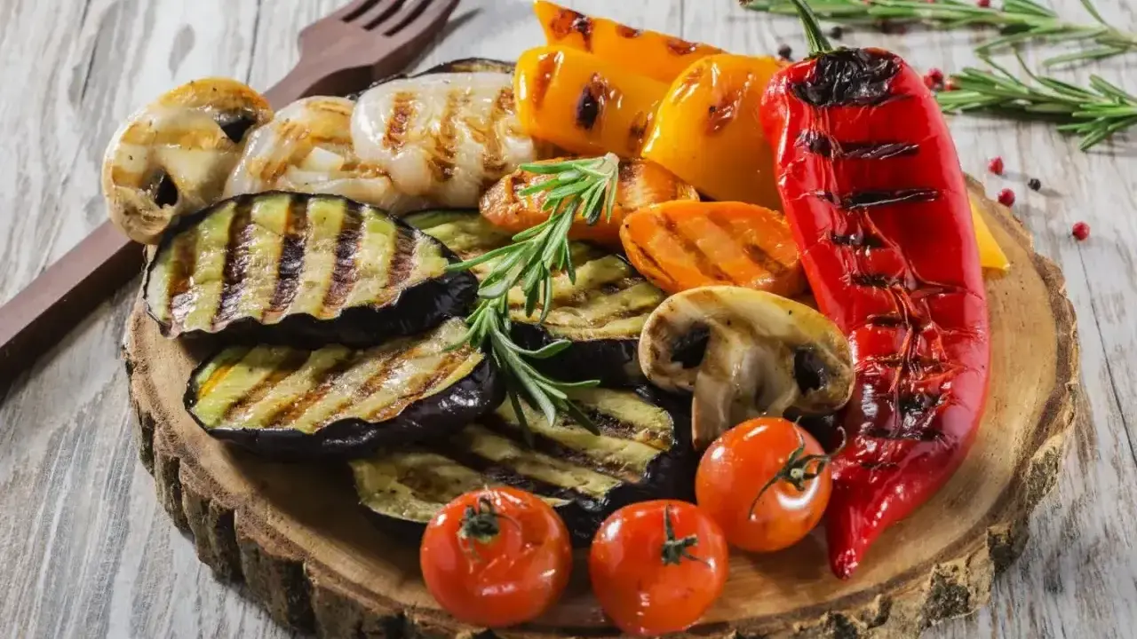 Pyszne warzywa na grilla: grillowany bakłażan, papryka, pieczarki, pomidorki i czerwona papryka, udekorowane rozmarynem.