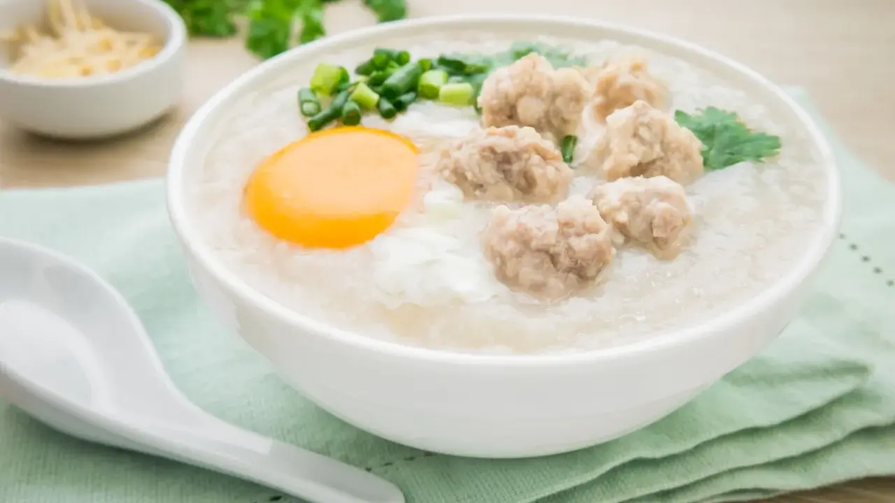 Miseczka aromatycznego congee z mięsnymi klopsikami, jajkiem i szczypiorkiem.