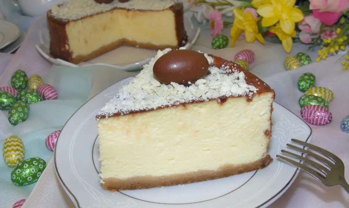 Wspaniały sernik z mascarpone, udekorowany czekoladowymi jajeczkami i wiórkami białej czekolady, idealny na Wielkanoc.