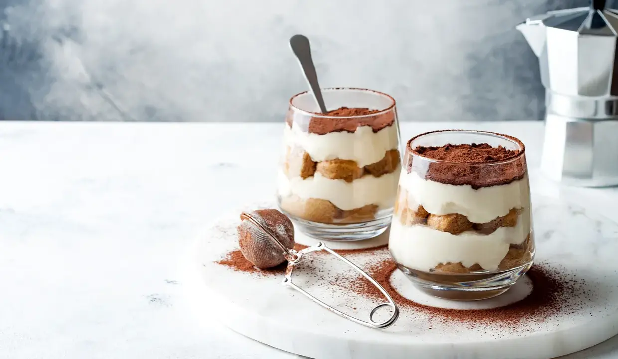 Dwa pucharki z kremowym, warstwowym deserem z biszkoptów i kakao. Idealne na najprostsze tiramisu.