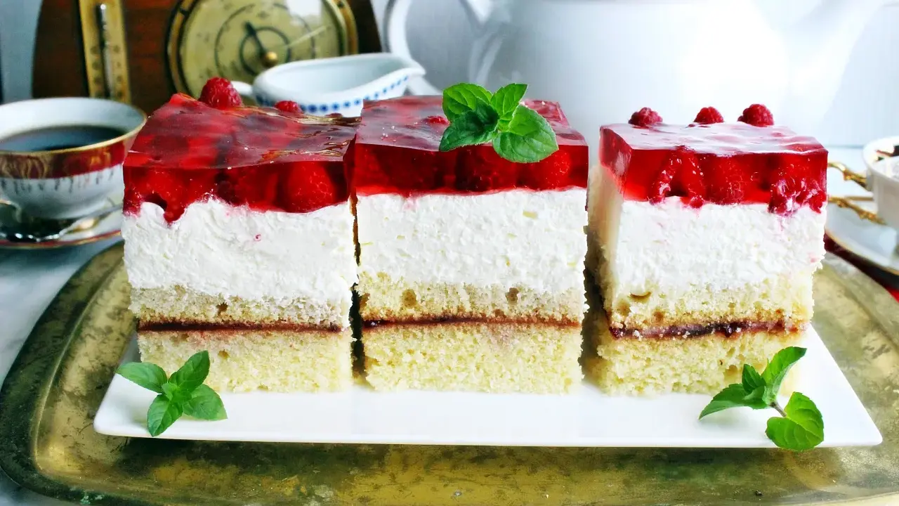 Pyszny biszkopt z serkiem mascarpone i bitą śmietaną, przełożony dżemem, z galaretką truskawkową i malinami.