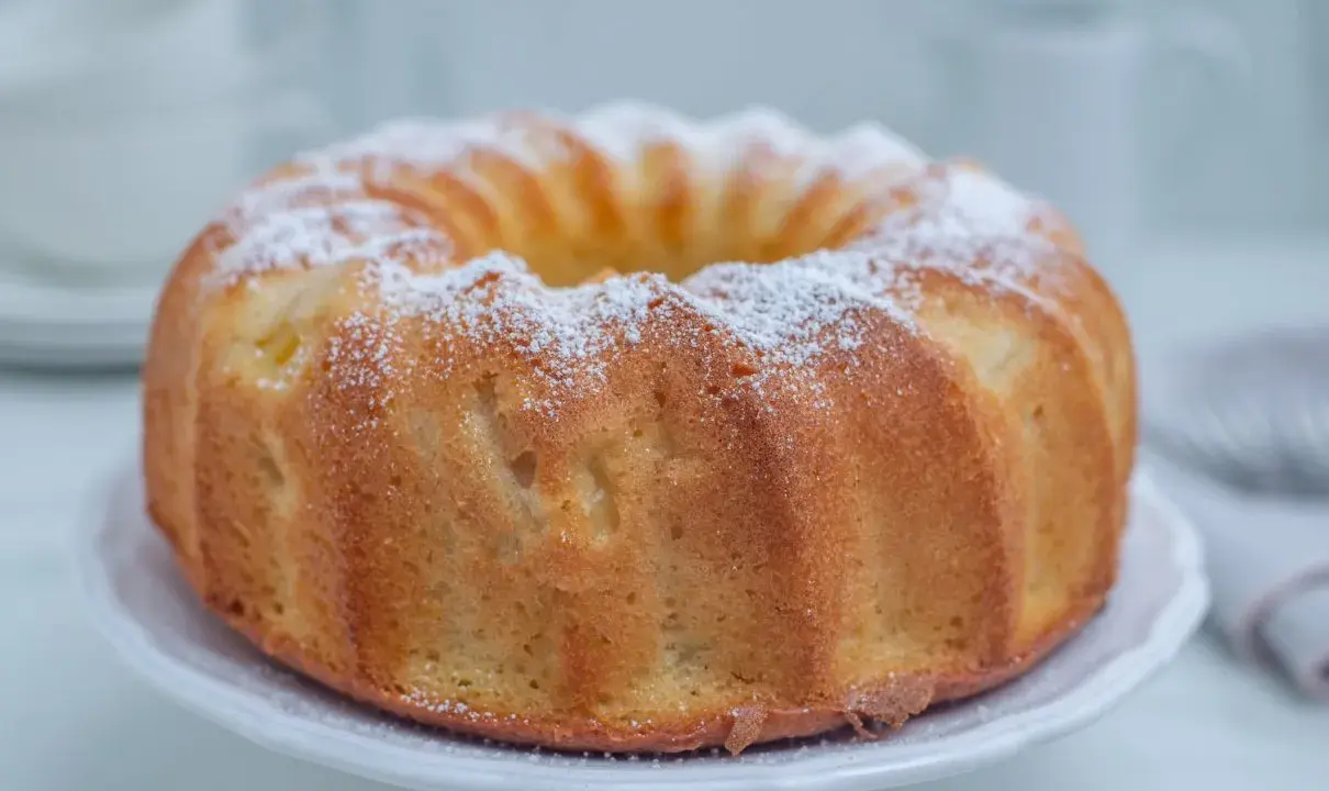Puszysta babka cytrynowa na oleju Ewy Wachowicz, oprószona cukrem pudrem, prezentuje się apetycznie na białej paterze.