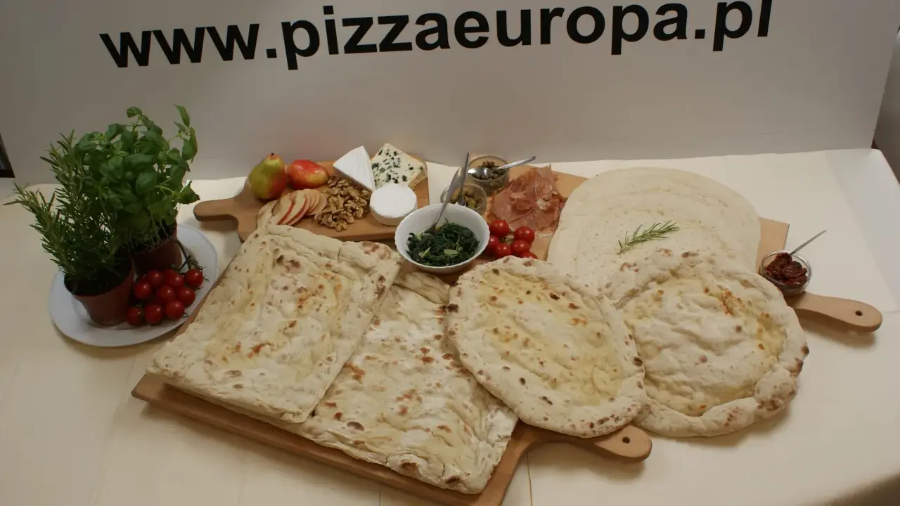 Gotowe ciasto na pizzę, świeże zioła, pomidorki, ser i inne dodatki na drewnianych deskach. Idealne na domowe wypieki.