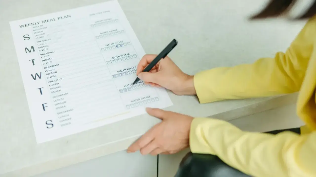 Planowanie posiłków na tydzień, w tym menu na weekendowe grillowanie. Kobieta zaznacza wypite szklanki wody.