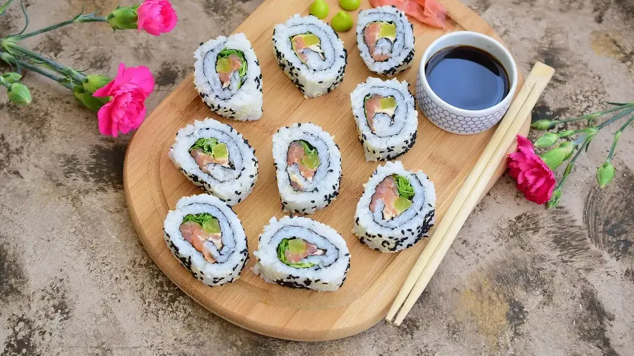 California sushi z łososiem i awokado, posypane czarnym sezamem, podane z sosem sojowym i wasabi.