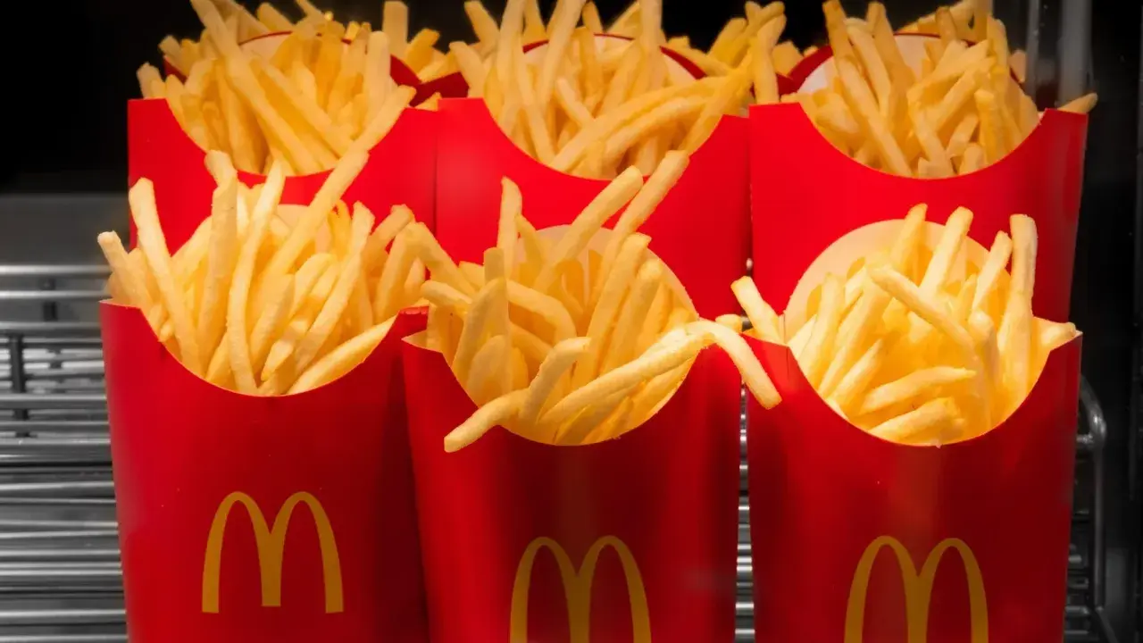 Rzędy czerwonych opakowań z logo McDonald's, wypełnione chrupiącymi frytkami. Zastanawiasz się, ile kosztują małe frytki w McDonald's?