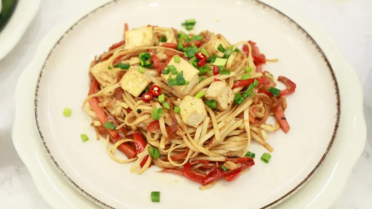 Pyszny makaron z tofu, papryką i szczypiorkiem, posypany chili. Idealne danie dla wegan.