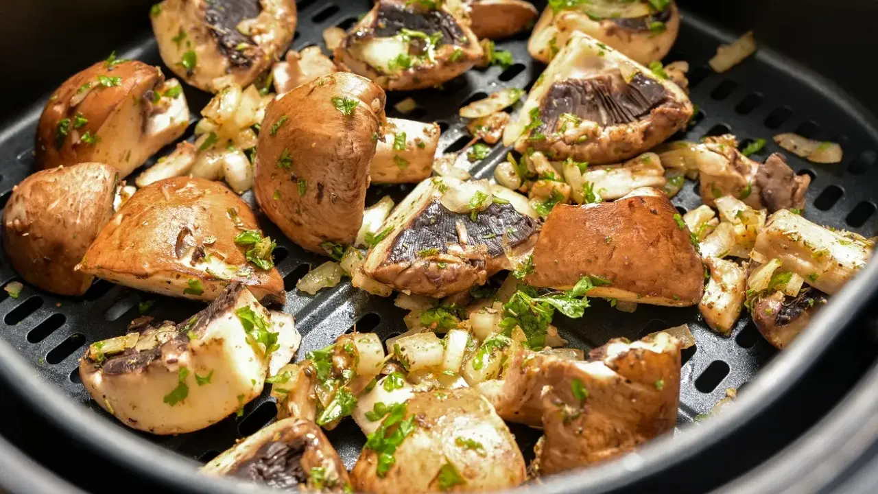 Pyszne pieczarki z airfryer, przyprawione i posypane natką pietruszki, gotowe do podania.