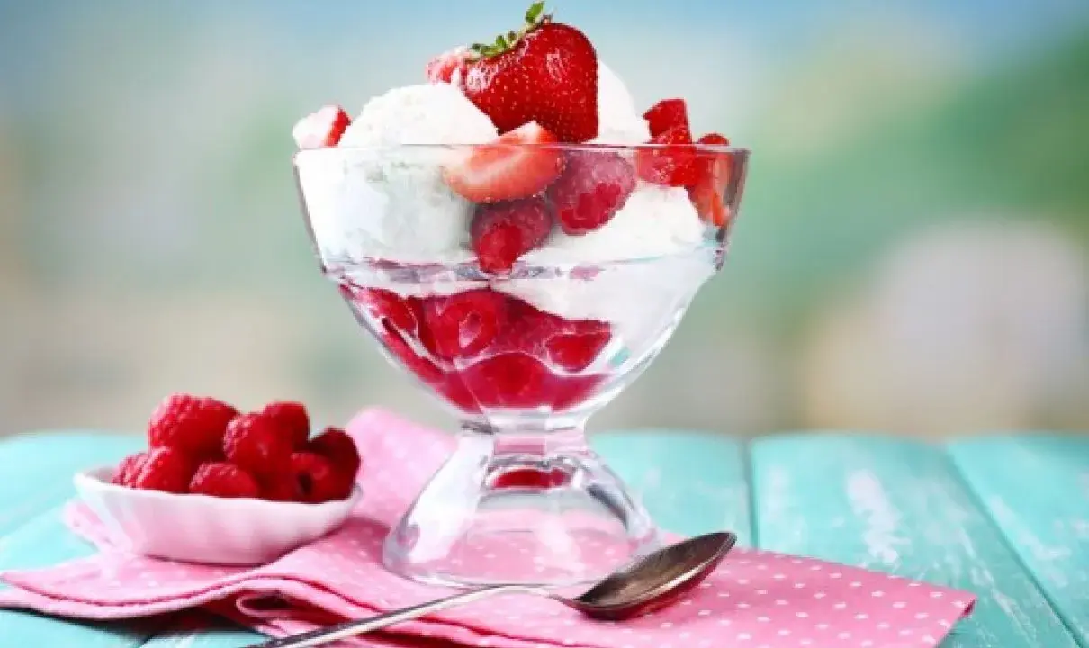 Pyszne lody nuii z malinami i truskawkami w pucharku.