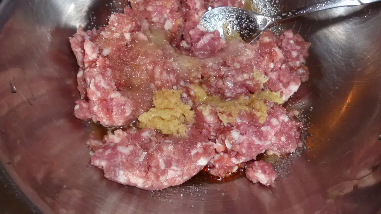 Mielone mięso z dodatkami, gotowe do przygotowania soboro. W metalowej misce znajduje się surowe mięso mielone, przyprawy i sos.
