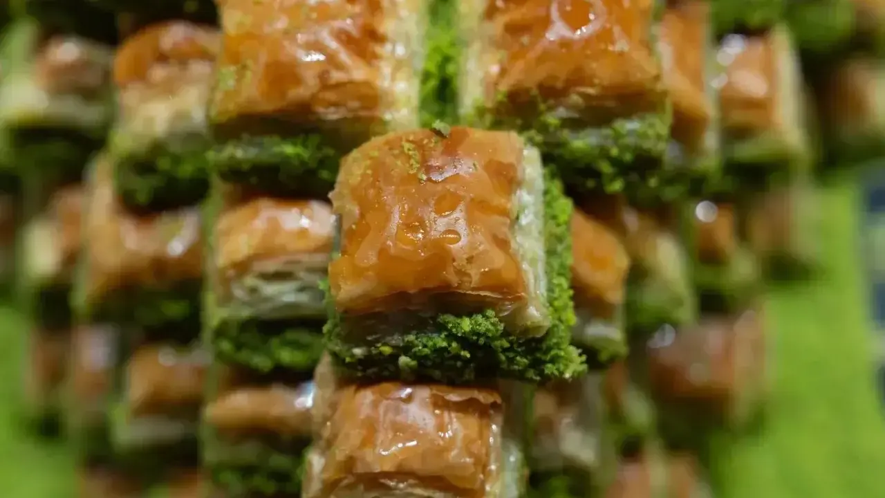 Słodka, złocista baklava, co to za przysmak! Warstwy ciasta filo, orzechów i syropu, posypane zielonymi pistacjami.