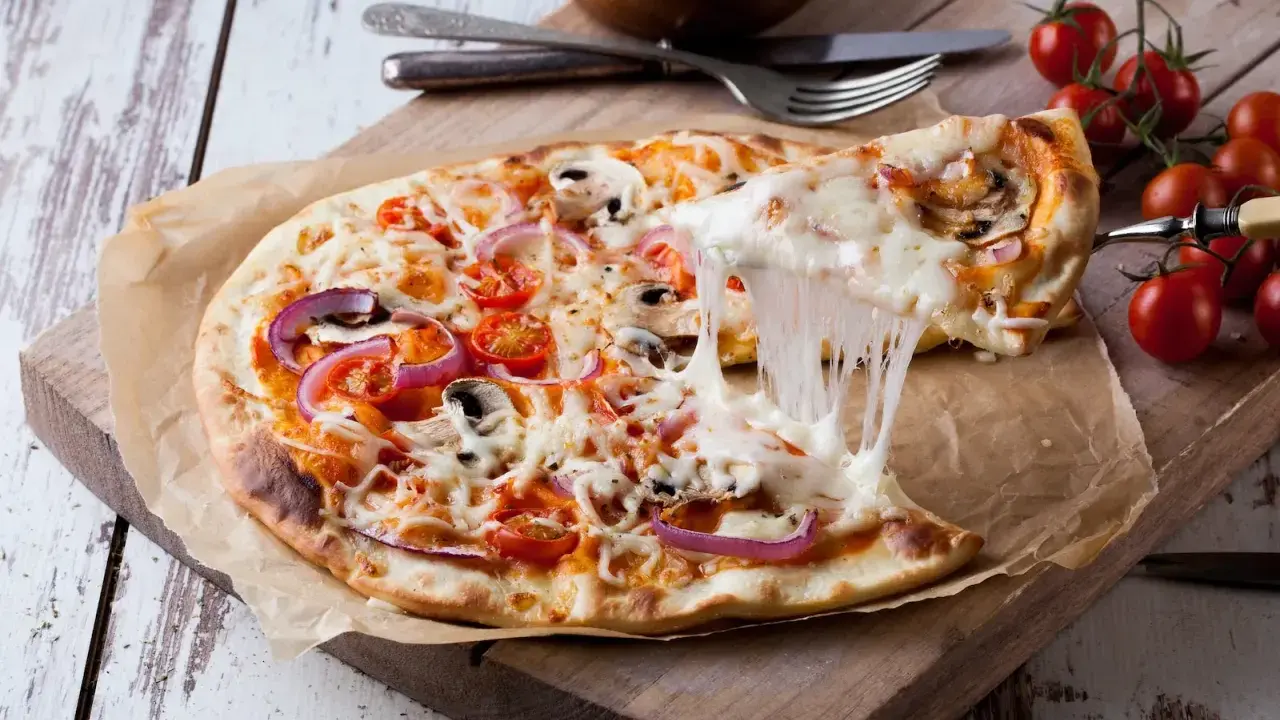 Ciągnący się ser z pizzy 32 cm z pomidorkami i cebulą. Zastanawiasz się, ile kcal ma pizza 32 cm?