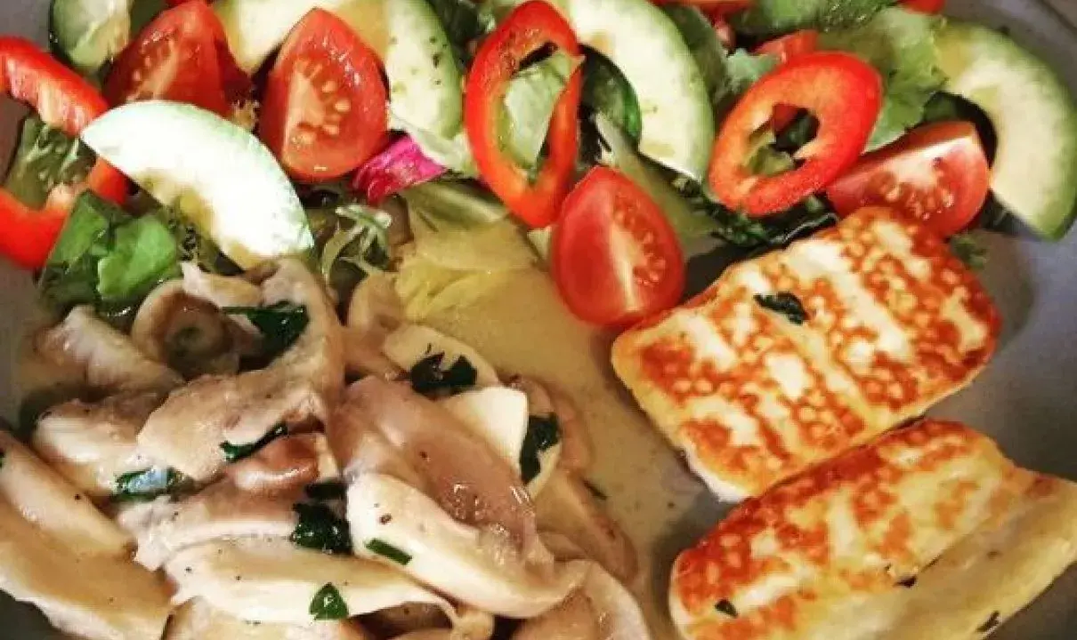 Pyszne halloumi z grilla podane z sałatką z awokado, pomidorów i papryki.