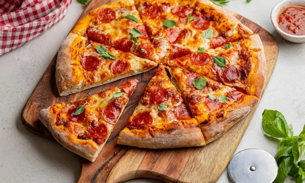 Pyszna pizza pepperoni z ciągnącym się serem i świeżą bazylią, gotowa do podania.