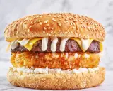 Apetyczny burger drwala przepis: soczysta wołowina, chrupiące panierowane ziemniaki, ser i biały sos na sezamowej bułce.