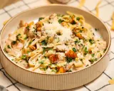 Pyszny makaron w sosie kurkowym z kawałkami kurczaka i posypany parmezanem.