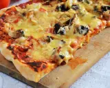 Pyszna pizza capriciosa z pieczarkami i szynką, roztopiony ser ciągnie się na chrupiącym cieście.