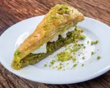 Pyszna baklawa z pistacjami i kremem na białym talerzu. Idealny przepis na deser.