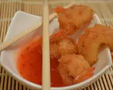 Chrupiące krewetki w panko, zanurzone w słodko-pikantnym sosie, gotowe do podania z pałeczkami.