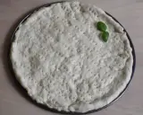 Gotowy do pieczenia, okrągły spód do pizzy z dziurkami, ozdobiony listkiem bazylii. Idealny szybki przepis na ciasto do pizzy.