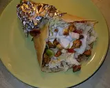 Pyszny kebab w tortilli z kurczakiem, warzywami i sosem na zielonym talerzu.