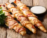 Pyszne paluszki z ciasta na pizzę owinięte boczkiem i posypane serem. Świetny pomysł na przekąskę!