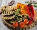 Pyszne warzywa na grilla: grillowany bakłażan, papryka, pieczarki, pomidorki i czerwona papryka, udekorowane rozmarynem.