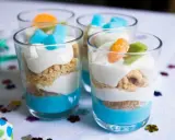 Kolorowy deser z mascarpone i galaretką w pucharkach, udekorowany owocami i kostkami galaretki. Idealny na letnie popołudnie.