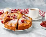 Błyskawiczne i super łatwe ciasto z owocami, posypane cukrem pudrem, z malinami i filiżanką herbaty.