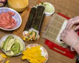 Przygotowanie uramaki: ryż, awokado, mango, krewetki i marynowany imbir czekają na zwinięcie w pyszne rolki sushi.