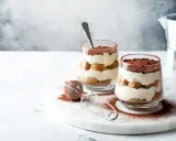 Dwa pucharki z kremowym, warstwowym deserem z biszkoptów i kakao. Idealne na najprostsze tiramisu.