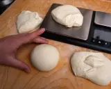Dłoń układa kulki ciasta na pizzę neapolitańską obok wagi. Idealne porcje do wypieku.