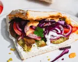 Pyszny falafel kebab w bułce z pomidorami, czerwoną cebulą, kapustą i sosami.