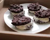 Cztery domowe ciastka Oreo z kremowym nadzieniem, ułożone na białym talerzu.