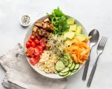 Kolorowa miska pełna zdrowych składników: pieczone tofu, pomidorki, awokado, ryż, kiełki, marchewka i ogórek. Idealna odpowiedź na pytanie, czy wegetarianie jedzą ryby – nie, ale jedzą pyszne, roślinne alternatywy!