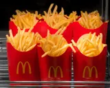 Rzędy czerwonych opakowań z logo McDonald's, wypełnione chrupiącymi frytkami. Zastanawiasz się, ile kosztują małe frytki w McDonald's?