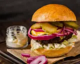 Soczysty burger z ogórkiem, czerwoną cebulą i majonezem, idealny do przygotowania, jak smażyć burgera na patelni.
