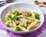 Penne z tuńczykiem i brokułami w kremowym sosie śmietanowo-serowym, udekorowane natką pietruszki.
