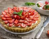 Pyszna tarta z truskawkami i kremem, ozdobiona listkami mięty. Idealna na letnie popołudnie.