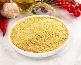 Biała miska pełna makaronu w kształcie ryżu, obok czosnek, chili, oliwa i pomidorki.