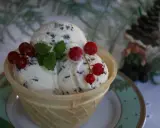 Lody straciatella w wafelku, ozdobione listkami mięty i czerwonymi porzeczkami.