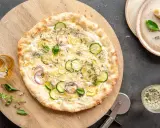 Pyszna pizza bianca z cukinią, cebulą i cytryną, posypana parmezanem i ziołami. Idealna na letni wieczór.
