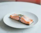Soczysty łosoś z airfryer, doprawiony pieprzem i świeżym koperkiem, prezentuje się apetycznie na białym talerzu.